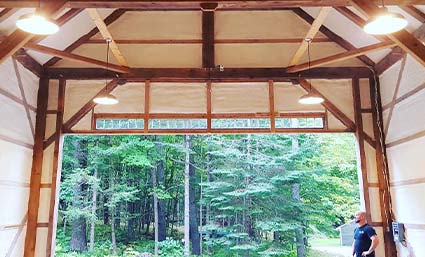 A man standing in the middle of a wooden barn in Maine.