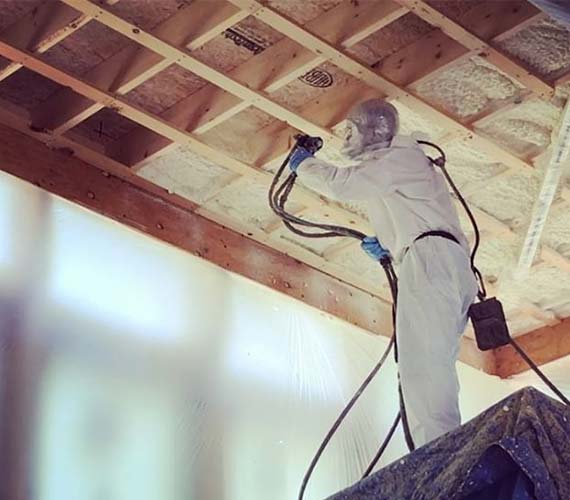 Insulation installer putting in spray insulation into ceiling. 