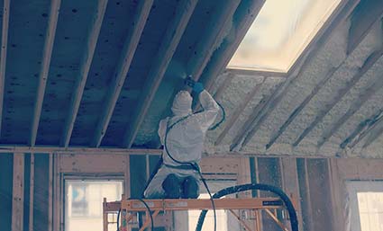 A man is spraying foam insulation in a house in Maine.